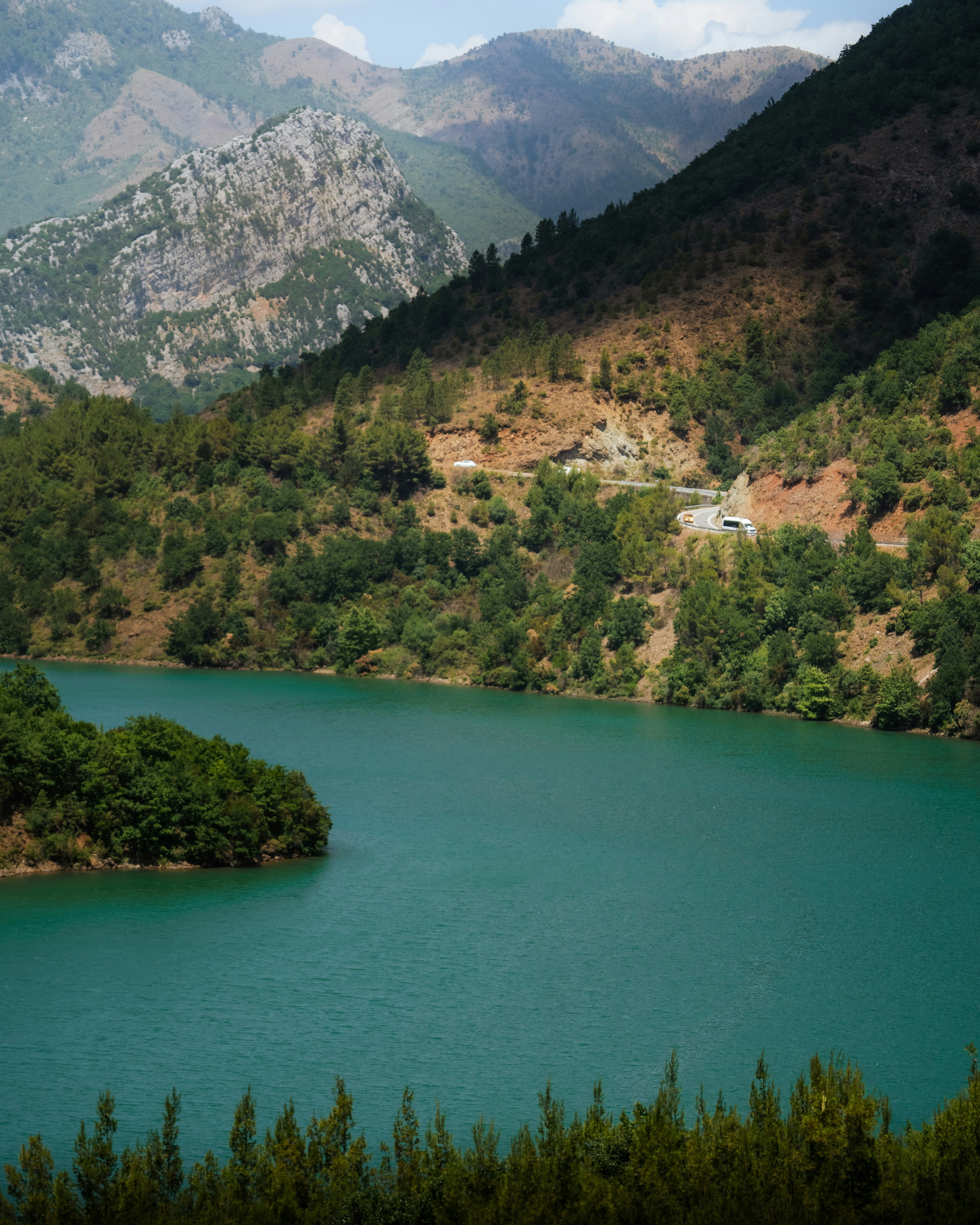 green lake surrounded by green trees and mountains during daytime